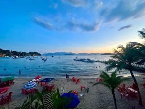einen Strand mit Stühlen und Booten im Wasser in der Unterkunft Duplex de Frente para a Praia - Angra Inn in Angra dos Reis