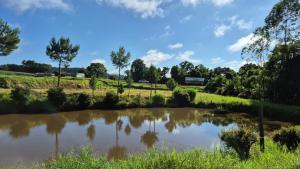 a pond in a field with trees in the background at Pousada Gaúcha Caibi in São Domingos
