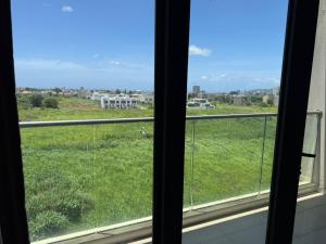 a window with a view of a green field at Le Meritt Appartments in Quatre Bornes