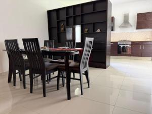 a dining room with a black table and chairs at Le Meritt Appartments in Quatre Bornes