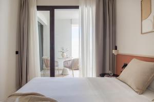 a bedroom with a white bed and a balcony at Líbere Seville Plaza Nueva in Seville