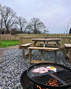 a picnic table and a grill with a picnic table and benches at Mill House Farm Pods- Jackdaws Den in Pilling