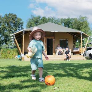 Ein kleines Kind mit Hut steht neben einem Ball in der Unterkunft Familie vakantiepark Krieghuusbelten in Raalte