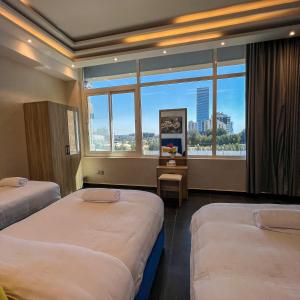 ein Hotelzimmer mit zwei Betten und einem großen Fenster in der Unterkunft Trio Sea View شقة تريو البحرية in Dschidda