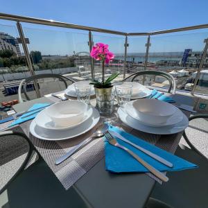 einen Tisch mit Tellern und Utensilien sowie eine rosa Blume in der Unterkunft Trio Sea View شقة تريو البحرية in Dschidda + 118 Fotos