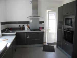 a kitchen with gray cabinets and a stove top oven at Conciergerie Gussy in Agon-Coutainville