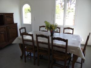 a dining room table with chairs and a vase of flowers on it at Conciergerie Gussy in Agon-Coutainville