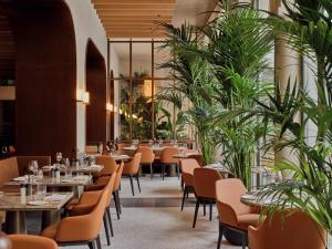 een restaurant met tafels, stoelen en planten bij The Florentin by Althoff Collection in Frankfurt am Main