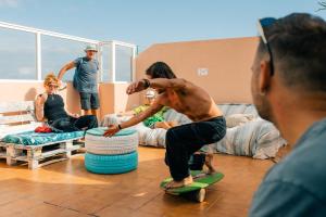 a man riding a skateboard in a room with people at Aloe Vera Shared House in El Médano +61 photos
