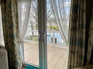 eine Glasschiebetür mit Blick auf ein Deck in der Unterkunft Lake Front 2 Bed Caravan, South Cerney in Cirencester
