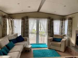 ein Wohnzimmer mit einer Couch und zwei Sesseln in der Unterkunft Lake Front 2 Bed Caravan, South Cerney in Cirencester