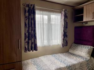 ein kleines Schlafzimmer mit einem Bett und einem Fenster in der Unterkunft Lake Front 2 Bed Caravan, South Cerney in Cirencester