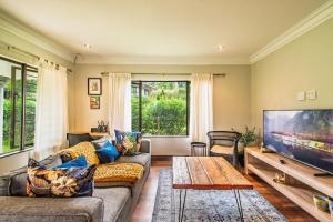 een woonkamer met een bank en een tv bij Robyns Nest Self Catering Cottage No4 in Gillitts