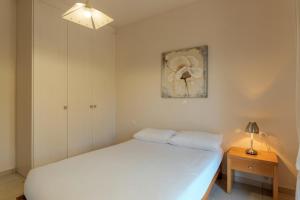 a white bedroom with a bed and a night stand at Lenika Residence in Sísai +29 photos