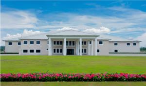 a large white building with a field of flowers at Royal Ambassador Hotel in Harbel