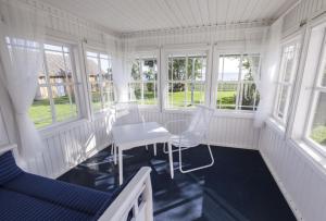 a white room with chairs and a table and windows at Käsmu Võrkneeme Apartments in Käsmu