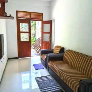 een woonkamer met een bank en een deur bij Stream Inn Haputale in Haputale