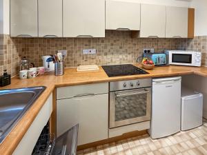 a kitchen with white cabinets and a stove top oven at Hindscarth in Keswick