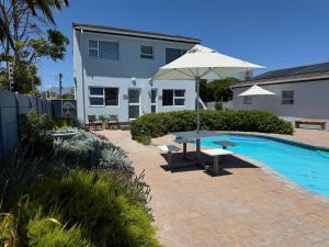 een terras met een tafel en een parasol naast een zwembad bij Southeaster in Bloubergstrand