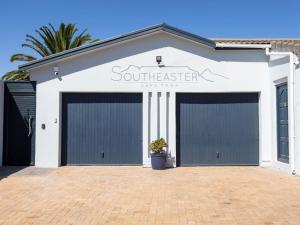 een wit gebouw met twee garagedeuren erop bij Southeaster in Bloubergstrand