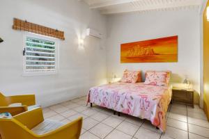 een slaapkamer met een bed en een stoel bij Barefoot Bonaire in Kralendijk +44 foto's