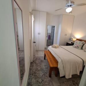 a white bedroom with a bed and a mirror at Albert's Nest in Kimberley