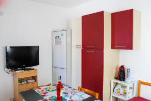 een keuken met een tafel, een koelkast en een televisie bij A Casuzza di Pina e Raffaele in Villaggio Azzurro