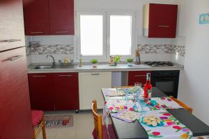 een keuken met een tafel en een keuken met rode kasten bij A Casuzza di Pina e Raffaele in Villaggio Azzurro +19 foto's