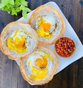 drie eieren op een wit bord op een houten tafel bij Stream Inn Haputale in Haputale