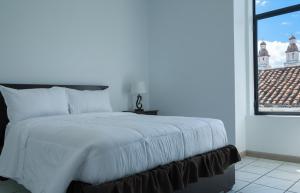 una camera da letto con un letto bianco con una grande finestra di Tikva Hotel a Cuenca