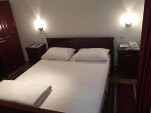 ein Schlafzimmer mit einem Bett mit zwei weißen Kissen und einem Telefon in der Unterkunft Vila Lux Milikic in Kraljevo