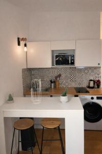eine Küche mit einer weißen Theke und 2 Hockern in der Unterkunft Studio Moderne, Le Carré Dor, À 3min Plage, NICE CENTRE in Nizza