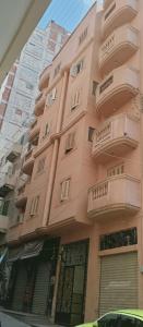 een roze gebouw met balkons aan de zijkant bij Apartment Alexandria City Center in Alexandrië