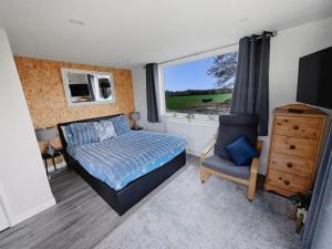 Meysey HamptonLakeview at The Hideaway的一间卧室，里面有一张床、一把椅子和一扇窗户。