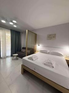 une chambre avec un grand lit blanc et une chaise dans l'établissement N apartments, à Néa Péramos 14 autres photos