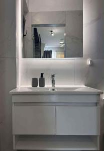 une salle de bains avec un lavabo blanc et un miroir dans l'établissement N apartments, à Néa Péramos