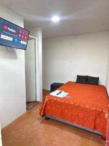 een slaapkamer met een bed met een oranje deken bij Monaco - Habitacion Mollendo in Inclán