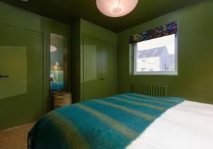 een groene slaapkamer met een bed en een raam bij Law View in North Berwick