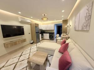 ein Wohnzimmer mit einem weißen Sofa und einem Fernseher in der Unterkunft Nubia El Karma Beach Resort & Aqua Park in Hurghada