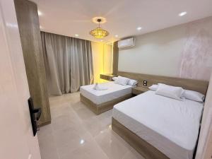 ein Hotelzimmer mit zwei Betten und einem Kronleuchter in der Unterkunft Nubia El Karma Beach Resort & Aqua Park in Hurghada + 142 Fotos