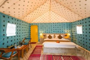 斋沙默尔Desert Villa Resort & Camp Jaisalmer的一间设有床铺的卧室,位于一间拥有蓝色墙壁的房间 更多125张照片