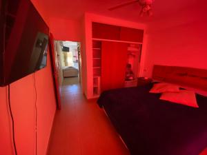 una camera da letto rossa con un letto e una tv di Deptos Drei Kinder a Belén de Escobar