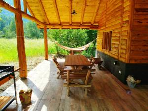 eine Holzterrasse mit einer Hängematte sowie einem Tisch und Stühlen in der Unterkunft Lejana Casa de montaña in Lago Puelo