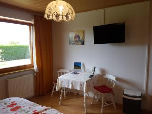a room with a table and a tv on the wall at Haus zur Sonne in Sankt Urban
