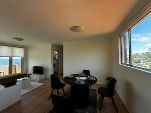 een woonkamer met een tafel en stoelen bij Beach & Ocean View Apartments Tamarama in Sydney +2 foto's
