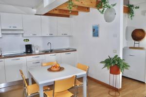 una cucina con tavolo bianco, sedie e lavandino di Windshouse Apartments a Torbole