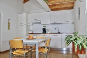 una cucina con mobili bianchi, tavolo e sedie bianchi di Windshouse Apartments a Torbole