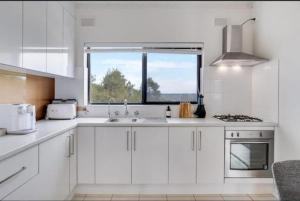 a white kitchen with a sink and a window at The Seaview at Semaphore Park in Port Adelaide