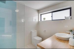 a bathroom with a sink and a toilet and a glass shower at The Seaview at Semaphore Park in Port Adelaide +30 photos