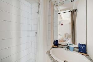 een witte badkamer met een wastafel en een douche bij Charming Studio - 2P - Sentier Montorgueil in Parijs